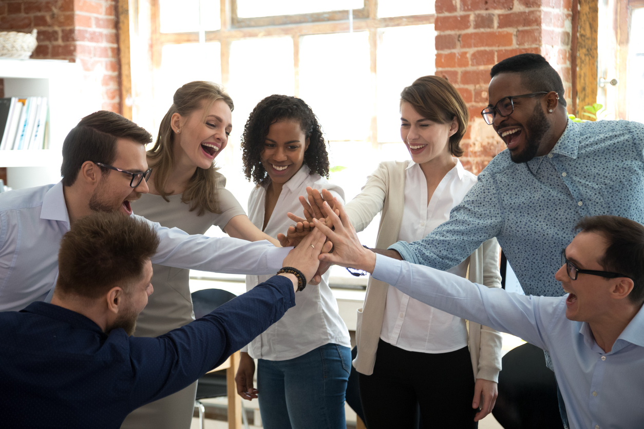 A happy group of coworkers giving each other a high-five together celebrating teamwork.